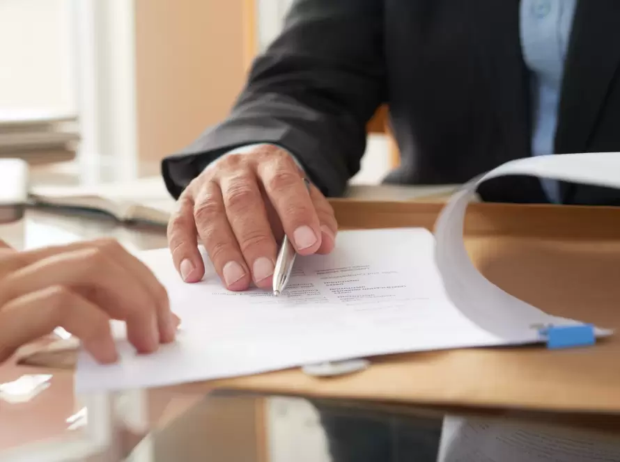 Manos de un profesional legal y un cliente, con el abogado señalando un punto en un documento. La imagen transmite la idea de recibir asesoramiento especializado, un paso crucial antes de impugnar un testamento en España.