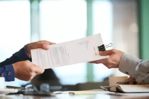 Hands exchanging legal documents, symbolizing the process of terminating an indefinite contract in Spain.