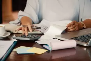 A professional calculating taxes with a calculator and tax documents. The image represents the process of understanding the Beckham Law and the main residence tax in Spain.