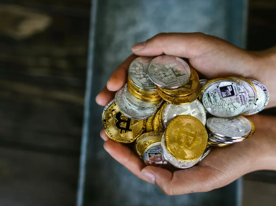 Primer plano de manos sosteniendo una pila de monedas de Bitcoin y otras criptomonedas, ilustrando la necesidad de gestionar la Fiscalidad de criptoactivos en España para inversores.