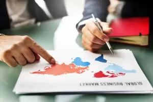 What Is International Taxation & How Can a Tax Lawyer Help You? 2 Two business people discussing a "Global Business Market" map, pointing to regions relevant for international taxation strategies and cross-border transactions.