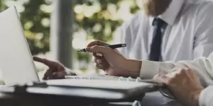 Two business professionals discussing and pointing at information on a laptop, symbolizing expert advisory and tax planning for a new LLC in Spain.