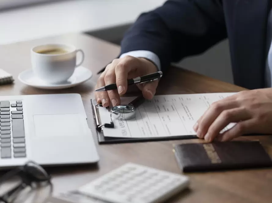 Taxation of LLCs in Spain: Essential Guide for International Business Owners and How to Set Up 3 Consultant reviewing an application form with a pen, magnifying glass, passport, and laptop on the desk, symbolizing the process of setting up an LLC in Spain.