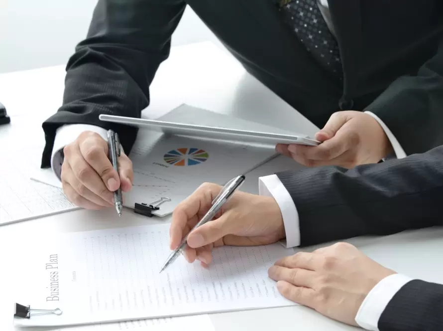 Two professionals reviewing a 'Business Plan' and financial charts, representing the strategic planning needed for Beckham Law for Directors.