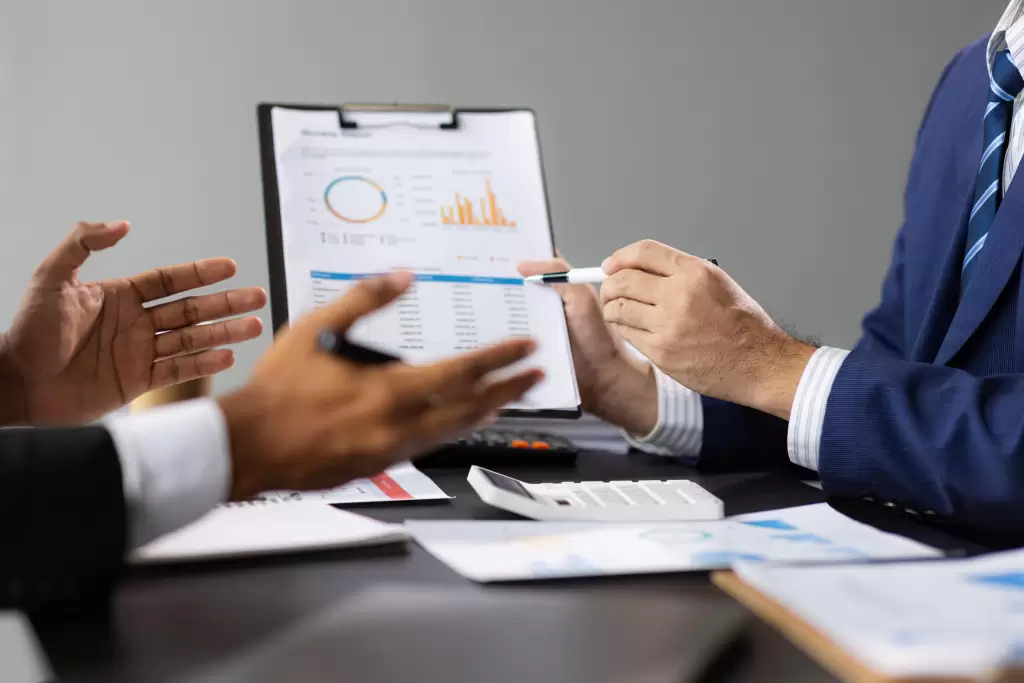 Two business people discussing financial reports with charts and graphs, representing expert advice for taxation after Beckham Law.