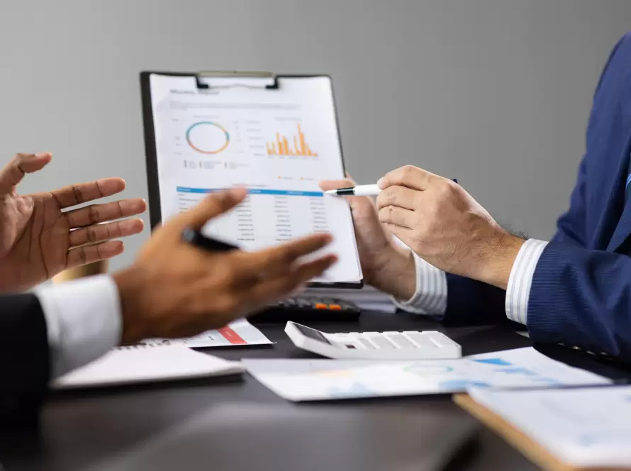 Two business people discussing financial reports with charts and graphs, representing expert advice for taxation after Beckham Law.