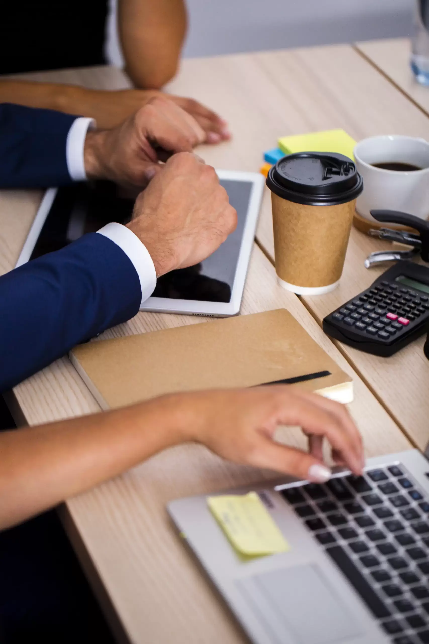 Reunión de negocios donde un asesor usa su laptop y una calculadora para ofrecer una completa asesoría fiscal para expatriados a clientes.