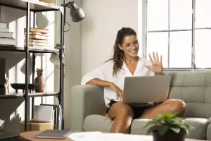 A smiling woman on a video call on her laptop from a home office, illustrating a remote worker in Spain potentially eligible for Beckham Law for Remote Workers.